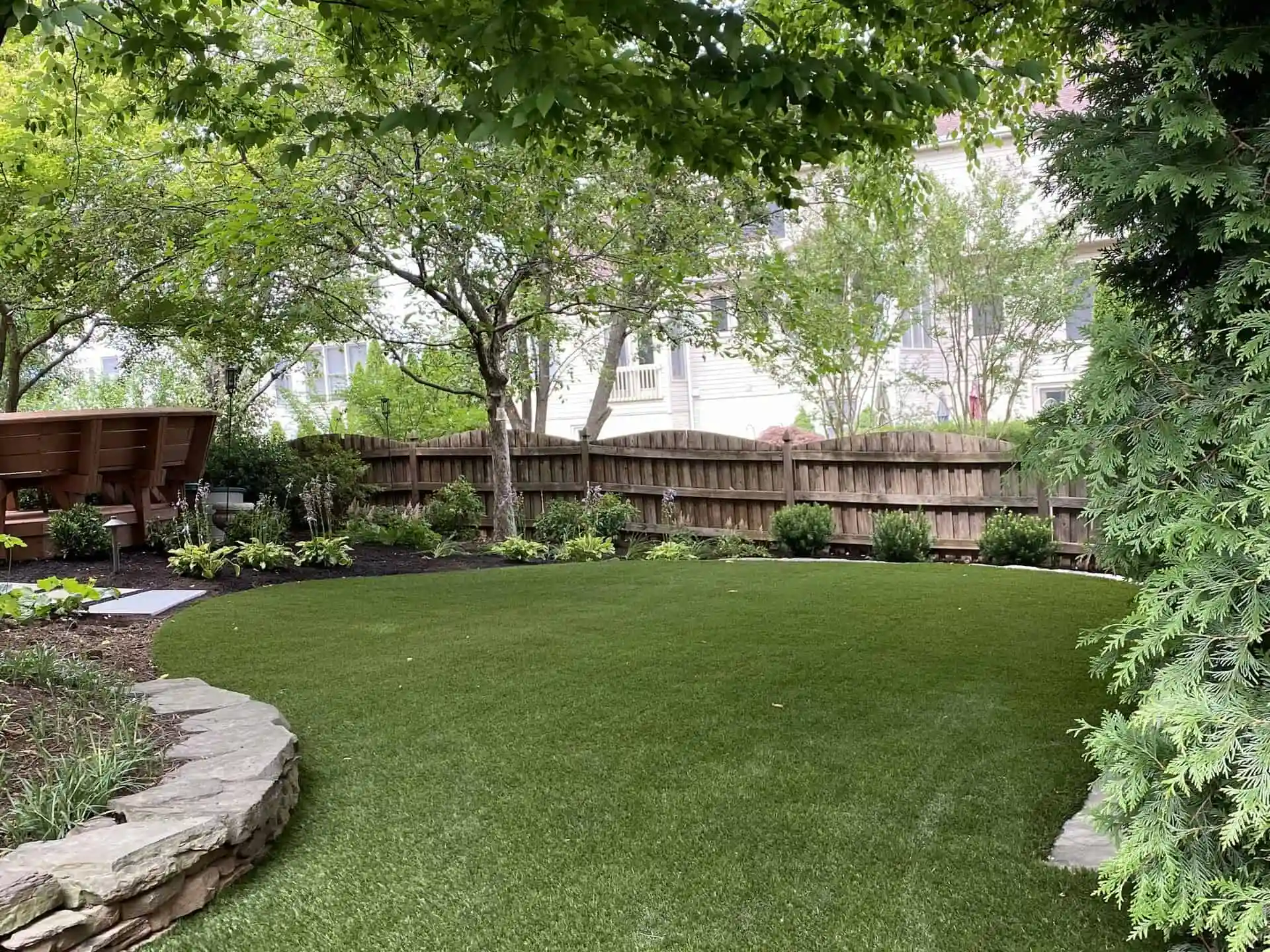 Finished artificial turf lawn in a landscaped backyard